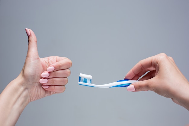 Brosse à dents dans les mains de la femme sur gris