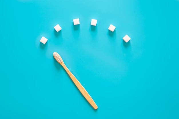 Photo gratuite brosse à dents avec des morceaux de sucre sur fond bleu à plat