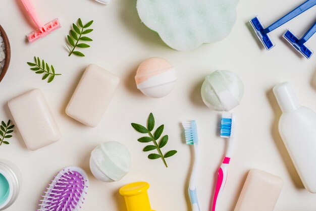 Brosse à dents; savon; bombe de bain; rose; produits de rasoir et cosmétiques sur fond blanc