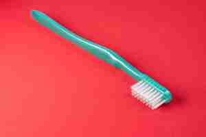 Photo gratuite brosse à dents verte sur la table rouge