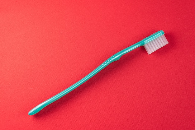 Photo gratuite brosse à dents verte sur la table rouge