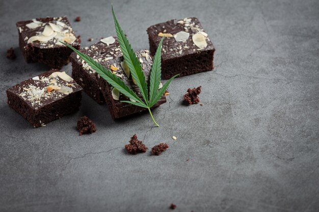 Brownies au cannabis et feuilles de cannabis posées sur un sol sombre