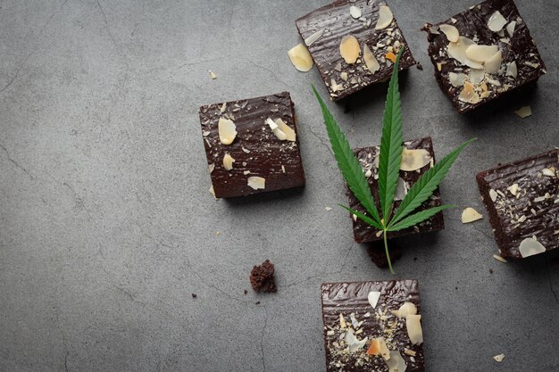 Brownies au cannabis et feuilles de cannabis posées sur un sol sombre