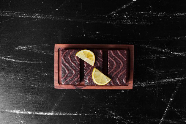 Brownies au chocolat sur une planche de bois avec des tranches de citron.