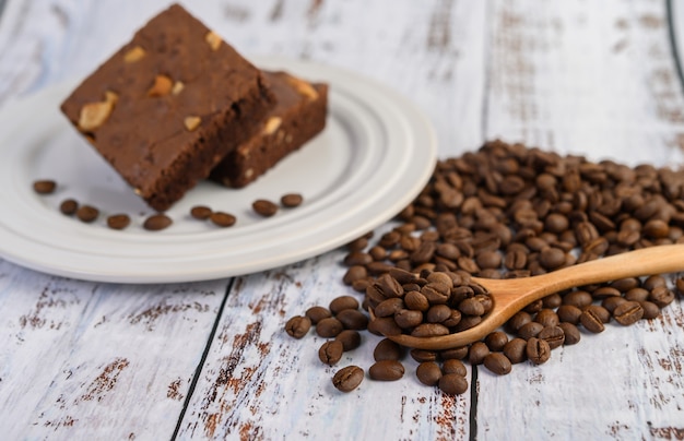 Brownies au chocolat sur une plaque blanche et grains de café sur une cuillère en bois.
