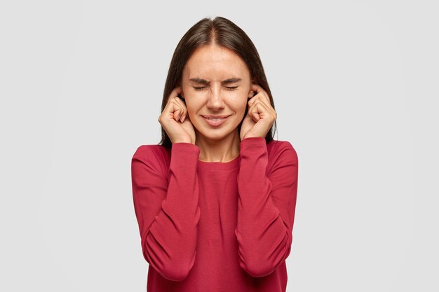 Une brune aux taches de rousseur stressante se bouche les oreilles