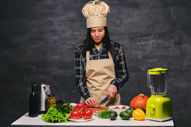 Brunette chef cuisinier féminin à la table préparant des repas végétaliens.