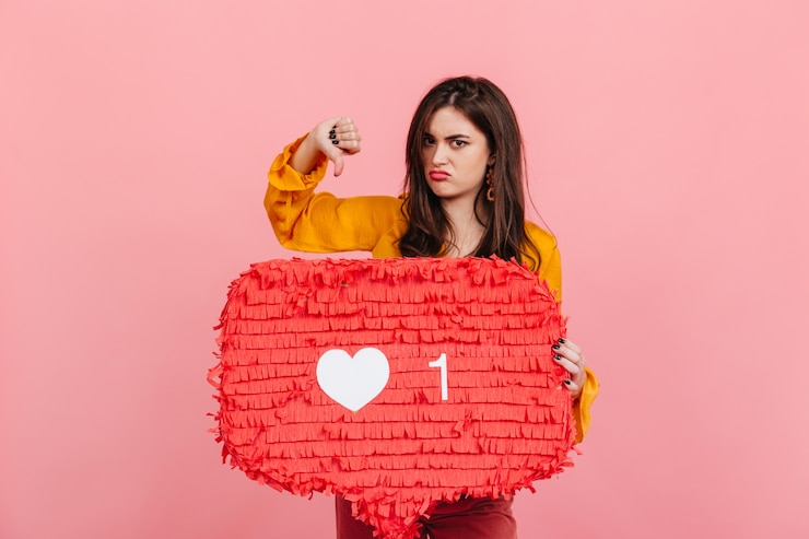 Photo gratuit brunette en chemisier jaune posant mécontent avec le pouce vers le bas, dénonçant les likes sur les réseaux sociaux.