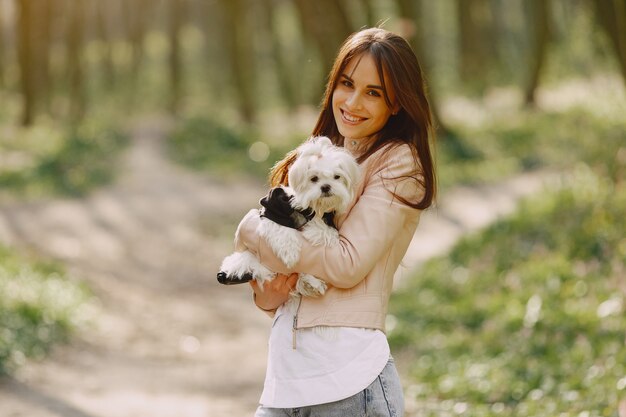 Brunette dans une forêt se promène avec un chien mignon