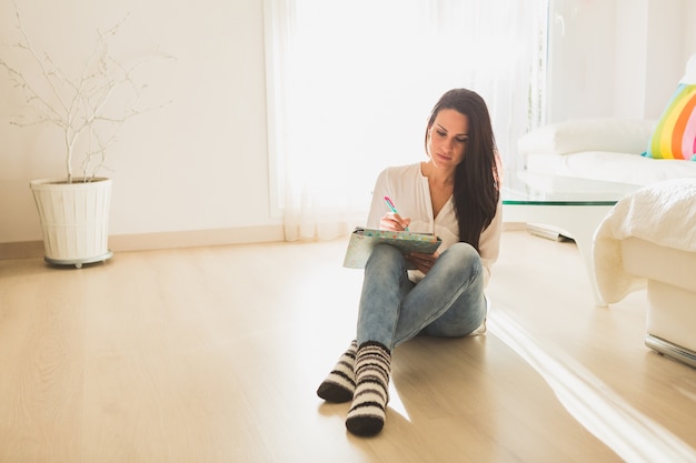 Brunette femme assise travaillant sur le plancher