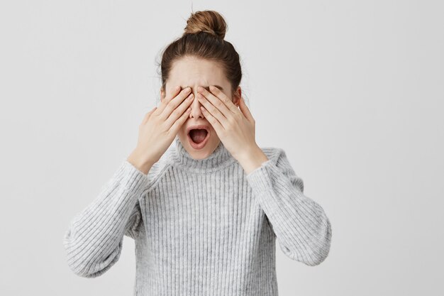 Brunette femme hurlant de peur couvrant les yeux avec les mains. Une jeune femme qui a peur ne veut pas voir ce qui s'est passé. Terreur, concept d'émotions