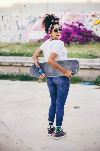 Brunette fille posant avec planche à roulettes