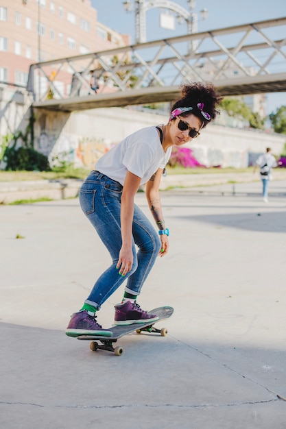 Brunette girl riding skateboard on street