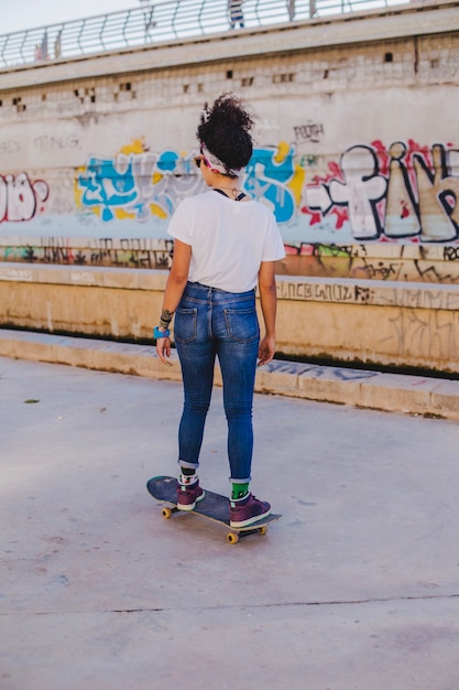 Brunette girl riding skateboard on street