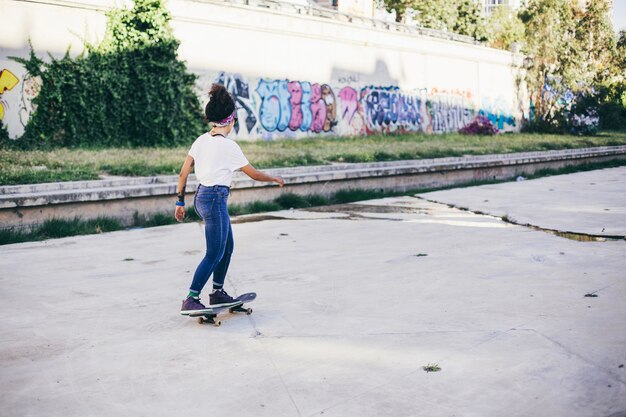 Brunette girl riding skateboard on street