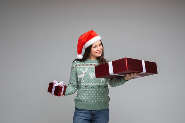 Brunette souriante regardant le cadeau de Noël dans les bras.