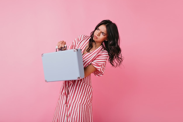 Brunette Tient Un Sac Super Lourd Et Pose émotionnellement. Fille Aux Cheveux Ondulés Posant En Mouvement.