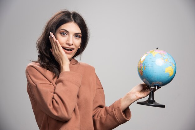 Photo gratuite brunette woman holding globe sur gris