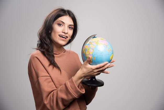 Brunette woman holding globe sur gris