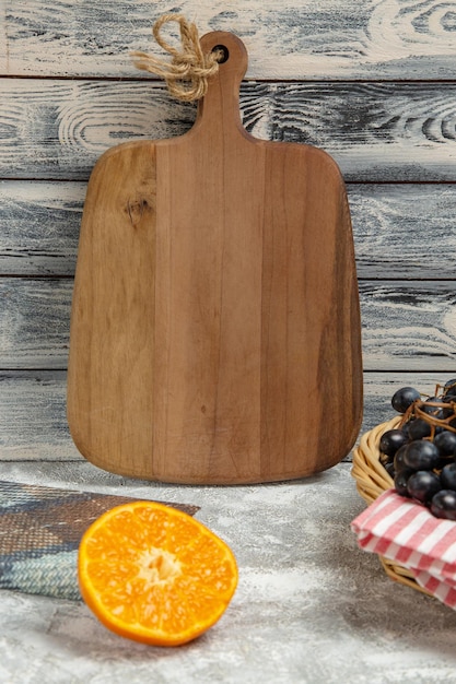 Photo gratuite bureau en bois marron vue de face avec des raisins oranges et noirs sur fond clair fruits mûrs frais