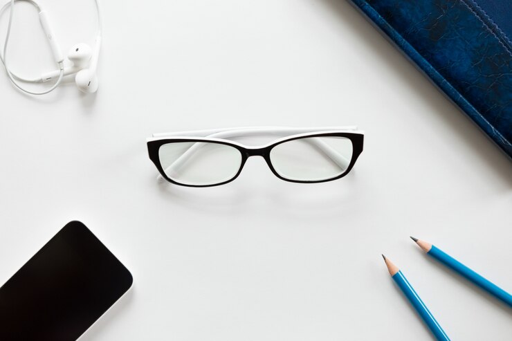 Photo gratuit bureau bureau blanc avec des lunettes, des crayons, des écouteurs et du mobile