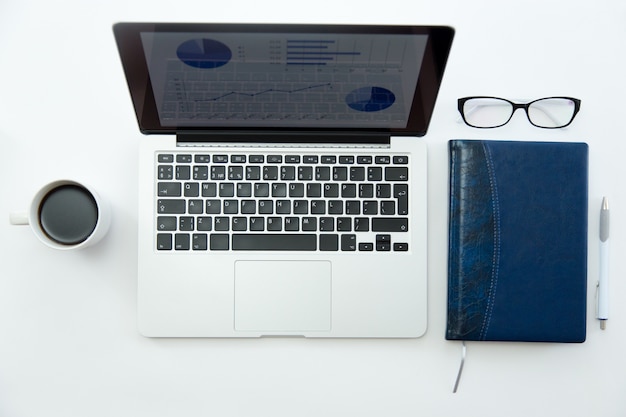 Bureau bureau blanc avec des lunettes, un ordinateur portable, un café et un cahier
