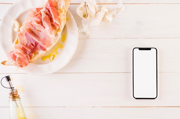 Bureau de cuisine avec sandwich et smartphone