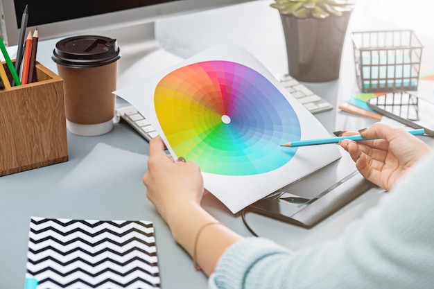 Le bureau gris avec ordinateur portable, bloc-notes avec feuille vierge, pot de fleur, stylet et tablette pour les retouches