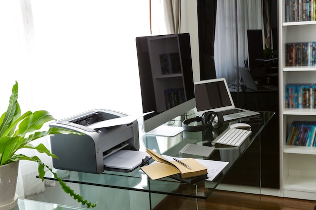 Bureau avec un ordinateur et une table en verre