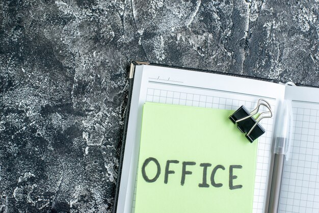 Bureau vue de dessus note écrite avec cahier et stylo sur fond gris