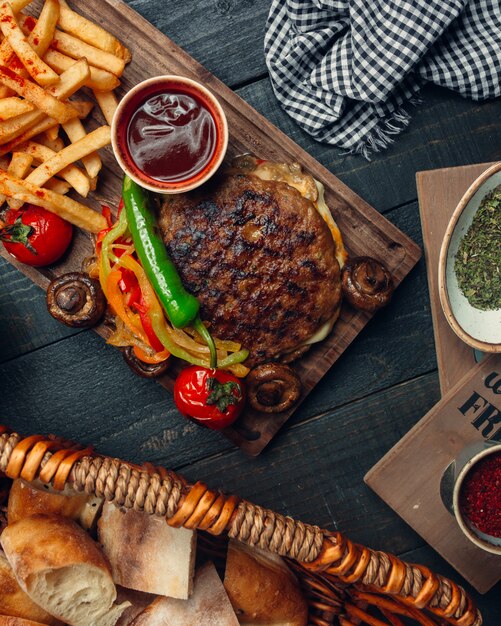 Burger d'agneau grillé sans pain servi avec poivrons grillés, frites, champignons, ketchup