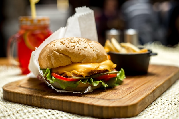 Burger au poulet ob planche en bois fromage laitue tomate concombre vue latérale