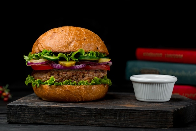 Burger de boeuf farci avec des ingrédients mélangés sur un tableau noir