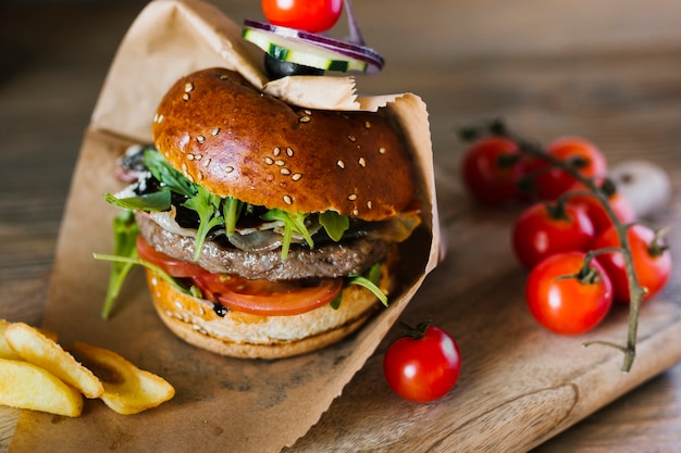 Burger gros plan angle avec frites sur planche de bois