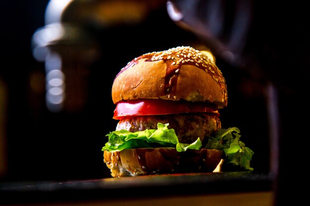 Burger de poulet sur planche de bois vue côté laitue tomate