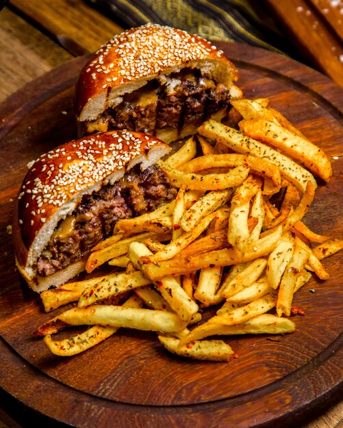 Burger de viande sur planche de bois frites vue latérale