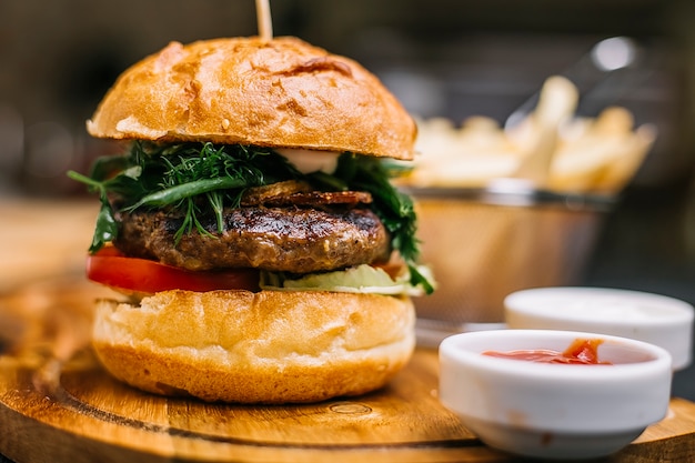 Burger de viande tomate concombre salade verte ketchup mayonnaise vue latérale