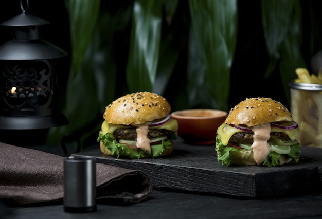 Burgers par deux personnes avec du fromage fondu complet sur un tableau noir