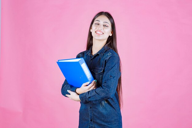 Businesswoman holding un dossier bleu avec confiance en soi