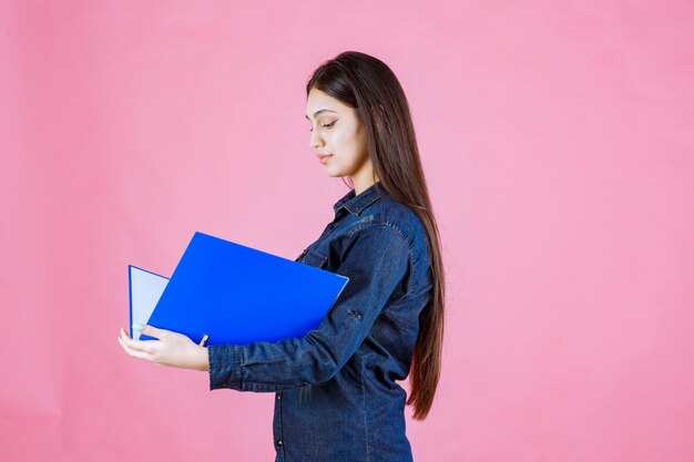 Businesswoman holding un dossier bleu avec confiance en soi