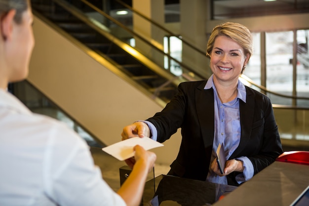 Businesswoman montrant sa carte d'embarquement au comptoir d'enregistrement