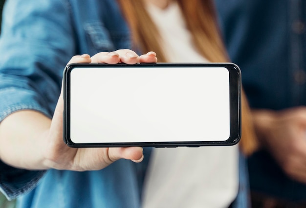 Businesswoman montrant un téléphone à écran vide