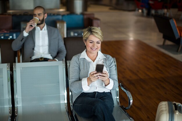 Businesswoman using mobile phone dans la zone d'attente