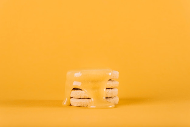 Photo gratuite cacao au citron dégoulinant sur une pile de biscuits sur fond jaune