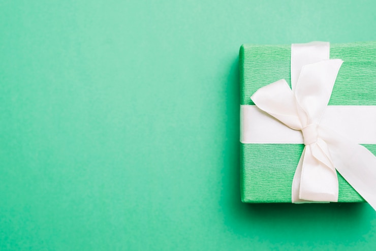 Photo gratuit cadeau d&#39;anniversaire emballé avec un ruban blanc sur fond vert