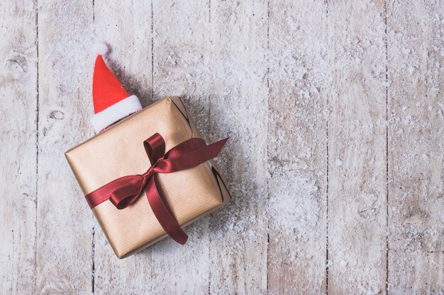 cadeau doré avec un arc rouge et un chapeau de Santa