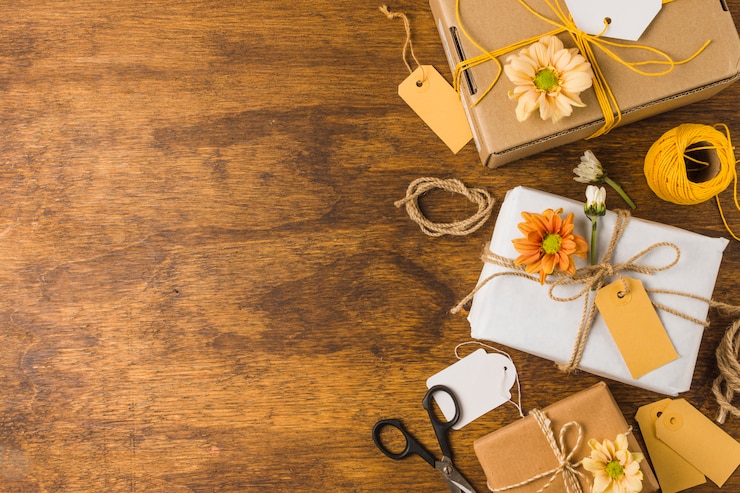 Photo gratuit cadeau emballé avec étiquette vide et belle fleur sur une table en bois