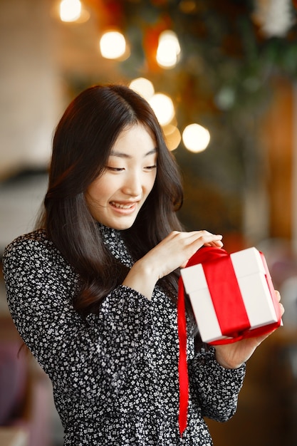 Cadeau femme en rouge tenant une boîte blanche. Beau modèle mixte caucasien / asiatique isolé. La Saint-Valentin.