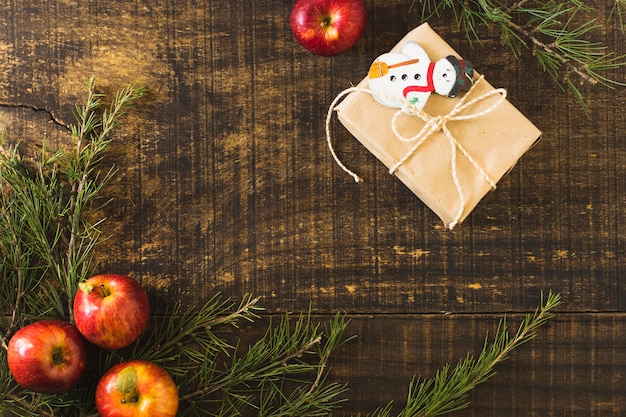 Photo gratuite cadeau de noël près des brindilles de conifères et des pommes