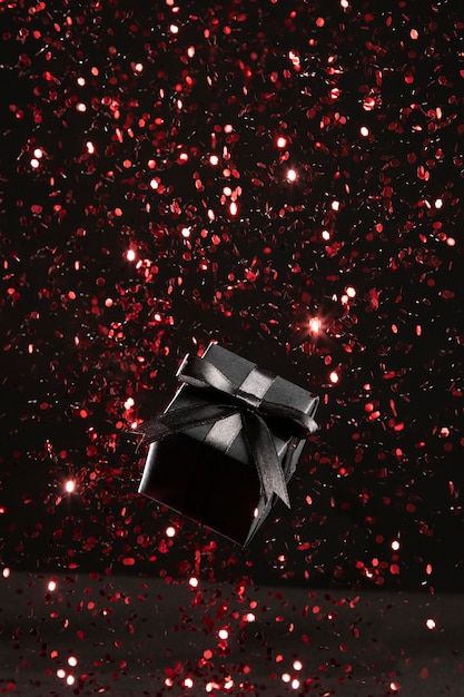 Photo gratuite cadeau noir avec assortiment de paillettes rouges